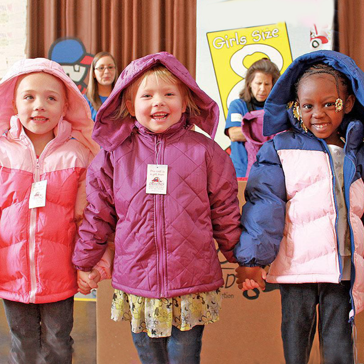 Three young kids wearing winter clothes and holding hands