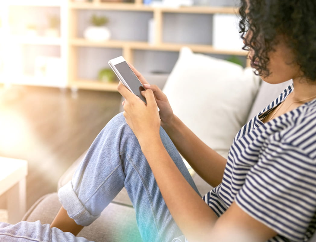 female sitting at home holding cell phone
