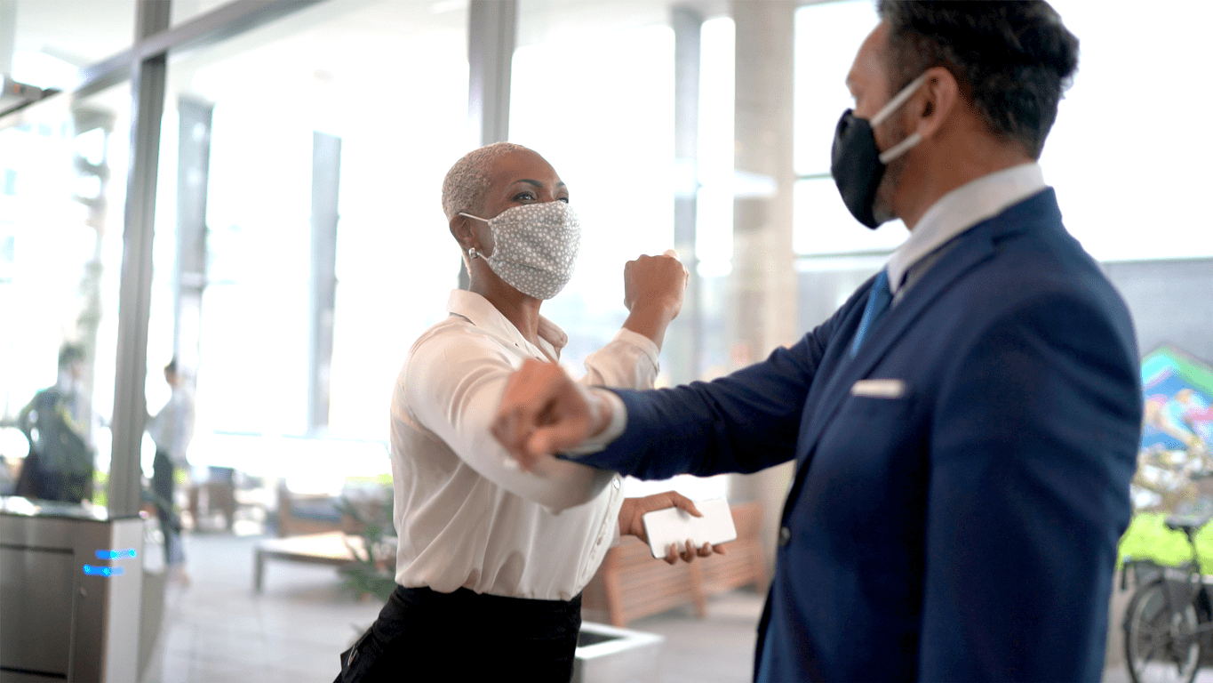 Two employees elbow shaking with masks on.